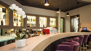 A bar area with a curved counter, purple chairs, and a white orchid in a glass container. - Atera Business Suites (Belgrade)