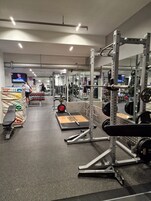 Ein Fitnessraum mit Krafttrainingsgeräten, einer Hantelbank und einem Spiegel.