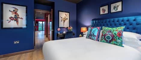Un dormitorio con una cama grande, un cabecero capitonado y dos cuadros florales enmarcados en la pared.