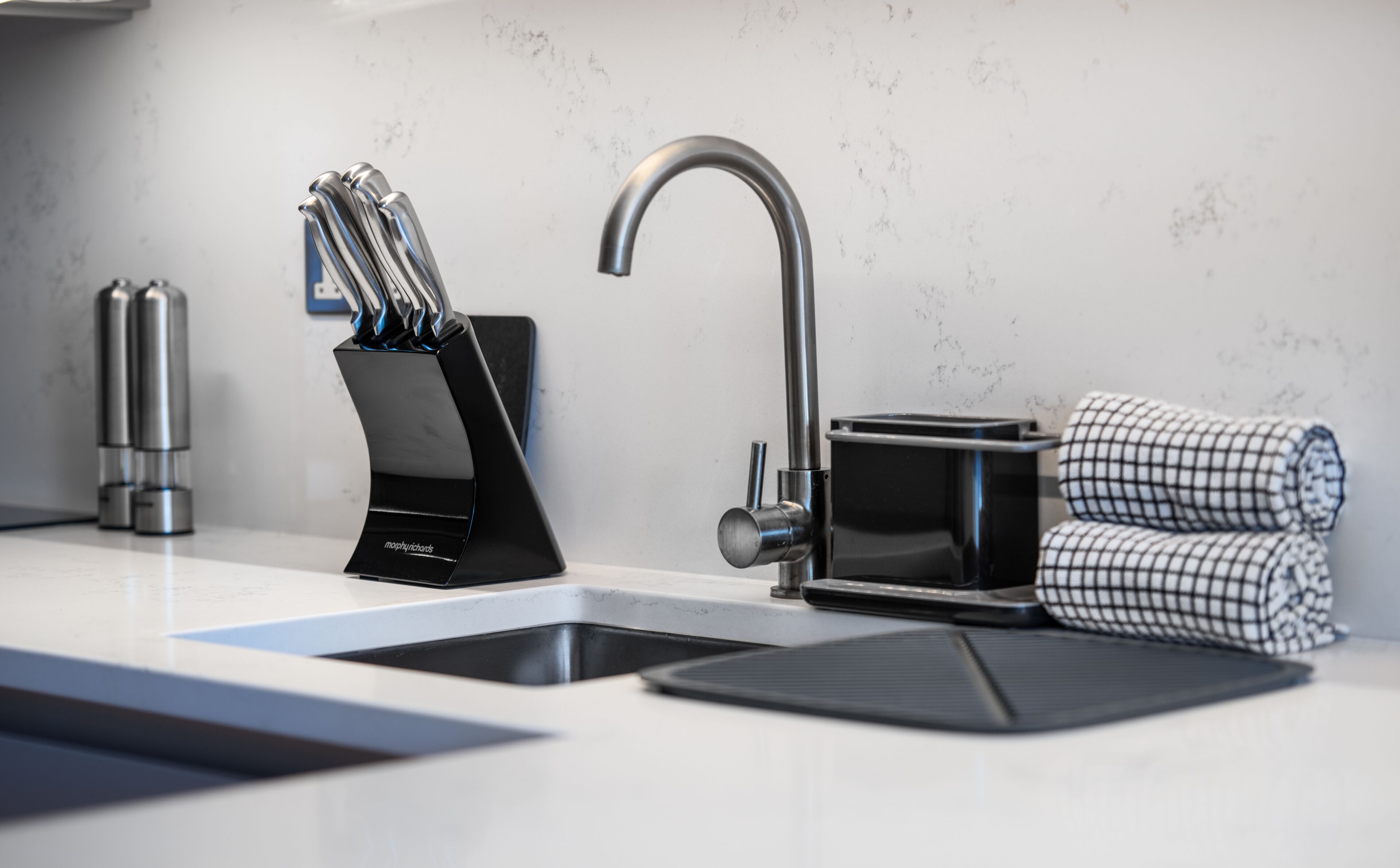 Une cuisine moderne avec un robinet élégant, un range-couteaux et un torchon à carreaux.