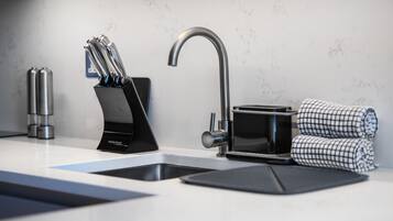 A modern kitchen with a sleek faucet, a knife block, and a checkered towel.