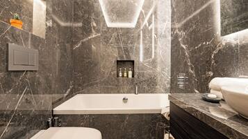 A modern bathroom with a large bathtub, a toilet, and a vanity with a sink.