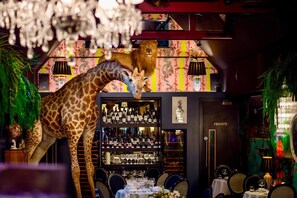 A restaurant with a giraffe statue, a wine bar, and a private dining area. - Hux Hotel (London)