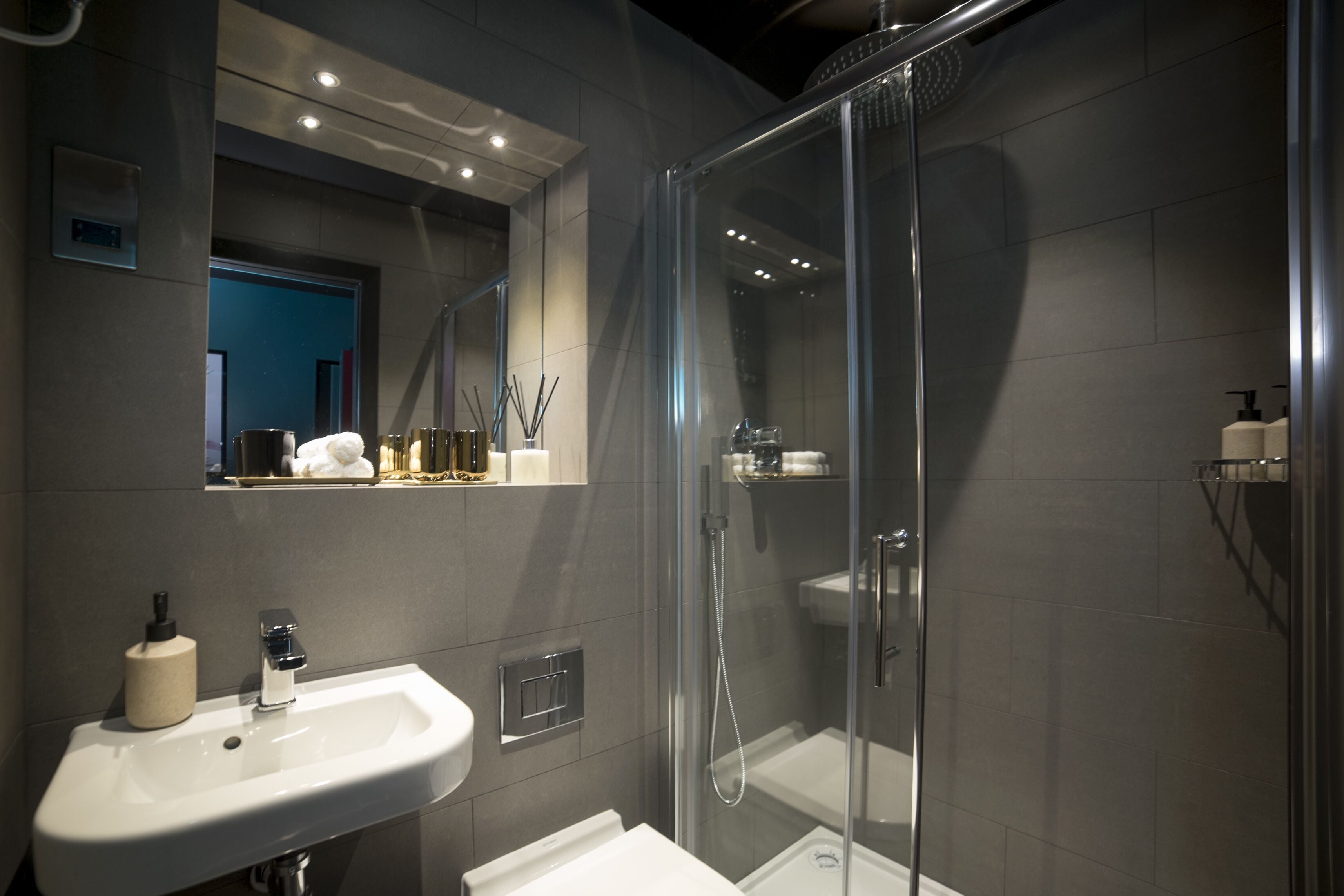 A modern bathroom with a glass-enclosed shower, a white sink, and a mirror above the sink.