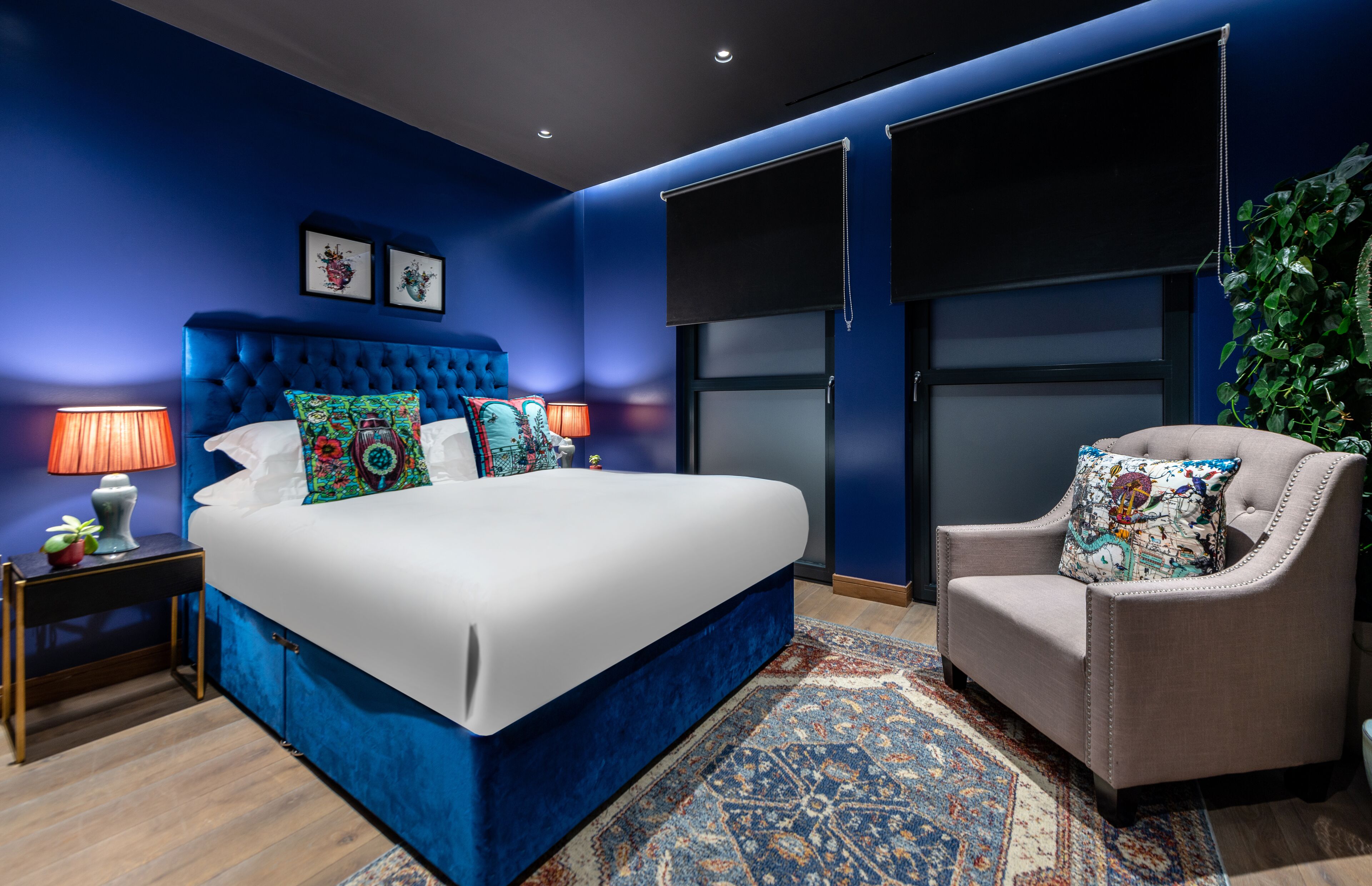 Ein Schlafzimmer mit einem großen Bett, einem Sessel, einem Nachttisch und einem großen Fenster.