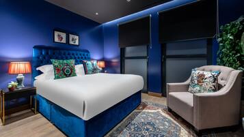 Ein Schlafzimmer mit einem großen Bett, einem Sessel, einem Nachttisch und einem großen Fenster.