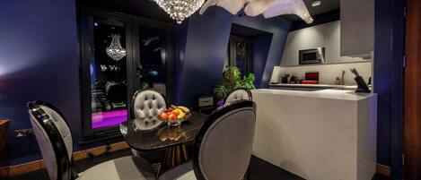 A modern dining area with a chandelier, a white bird sculpture, and a kitchen with a microwave.