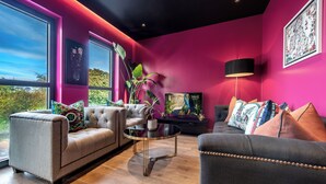 A modern living room with a large window, a sofa, a coffee table, and a TV.