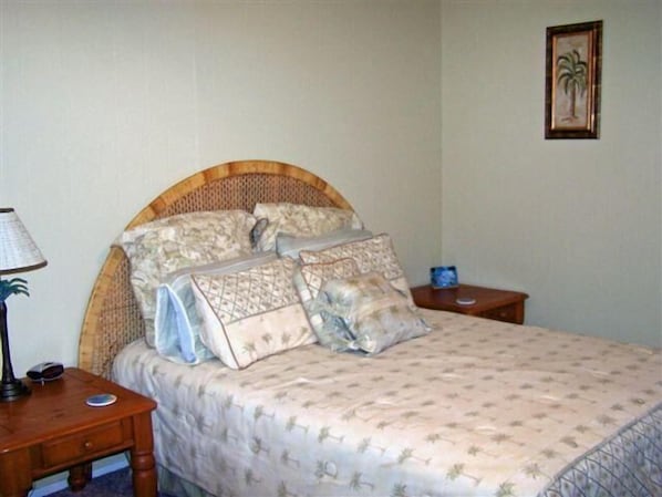 A bedroom with a bed, a nightstand, a lamp, and a framed picture on the wall. - Mustang Bungalow 4MI (Port Aransas)