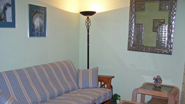 Una sala de estar con un sofá a rayas, una mesa de centro de vidrio y una lámpara de pie.