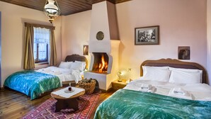 Ein gemütliches Zimmer mit zwei Betten, einem Kamin, einer Holzbalkendecke und einem gemusterten Teppich.