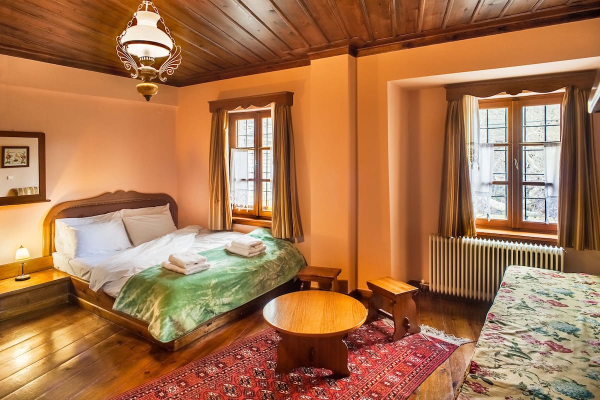 A cozy room with a wooden bed, a round wooden table, and a radiator.