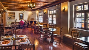 Ein traditioneller Speisesaal mit Holzmöbeln, einem Kamin und großen Fenstern.