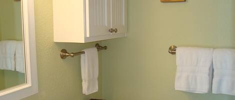 Une salle de bain équipée de toilettes, d’un porte-serviettes, d’un miroir et d’un petit panier contenant des articles de toilette.