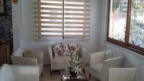 A living room with a sofa, two armchairs, a coffee table, and a window with blinds. - Murat Hotel (Kemer)