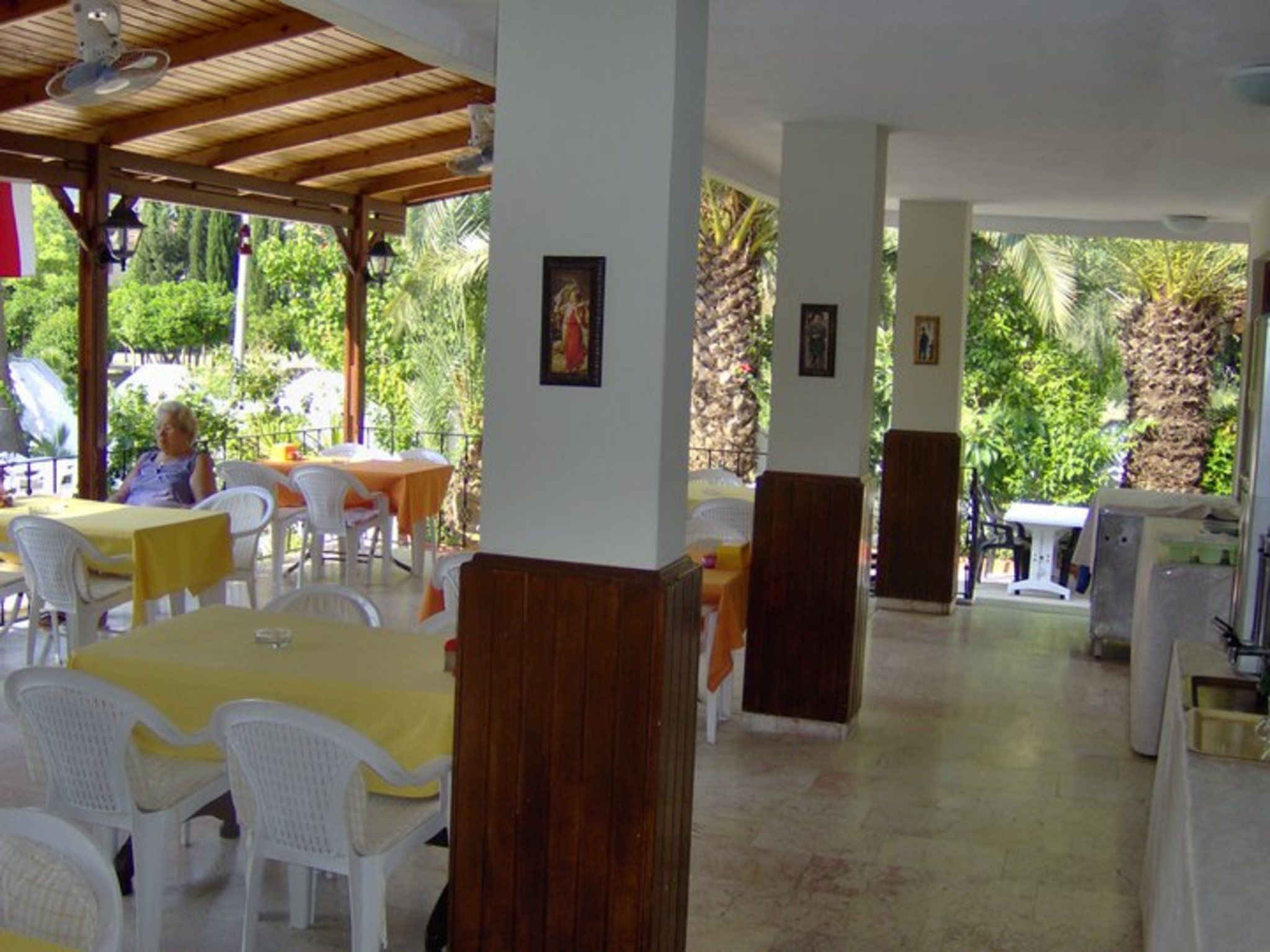 An outdoor dining area with tables and chairs, surrounded by greenery.