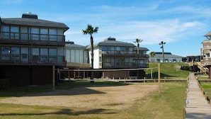 A beachside property with a wooden deck, a volleyball court, and multiple-story buildings with balconies. - Sunrise View 303BH (Port Aransas)