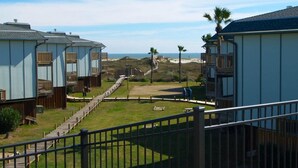 A beachfront property with multiple bungalow-style cabins, a wooden deck, and a clear view of the ocean. - Sunrise View 303BH (Port Aransas)