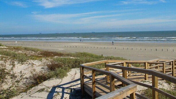 A beach with wooden boardwalks leading to the shore, sandy dunes, and the ocean. - Sunrise View 303BH (Port Aransas)