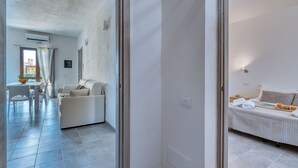 Una habitación de hotel moderna con cama, una mesita con frutero y un área de descanso con sofá y sillones.