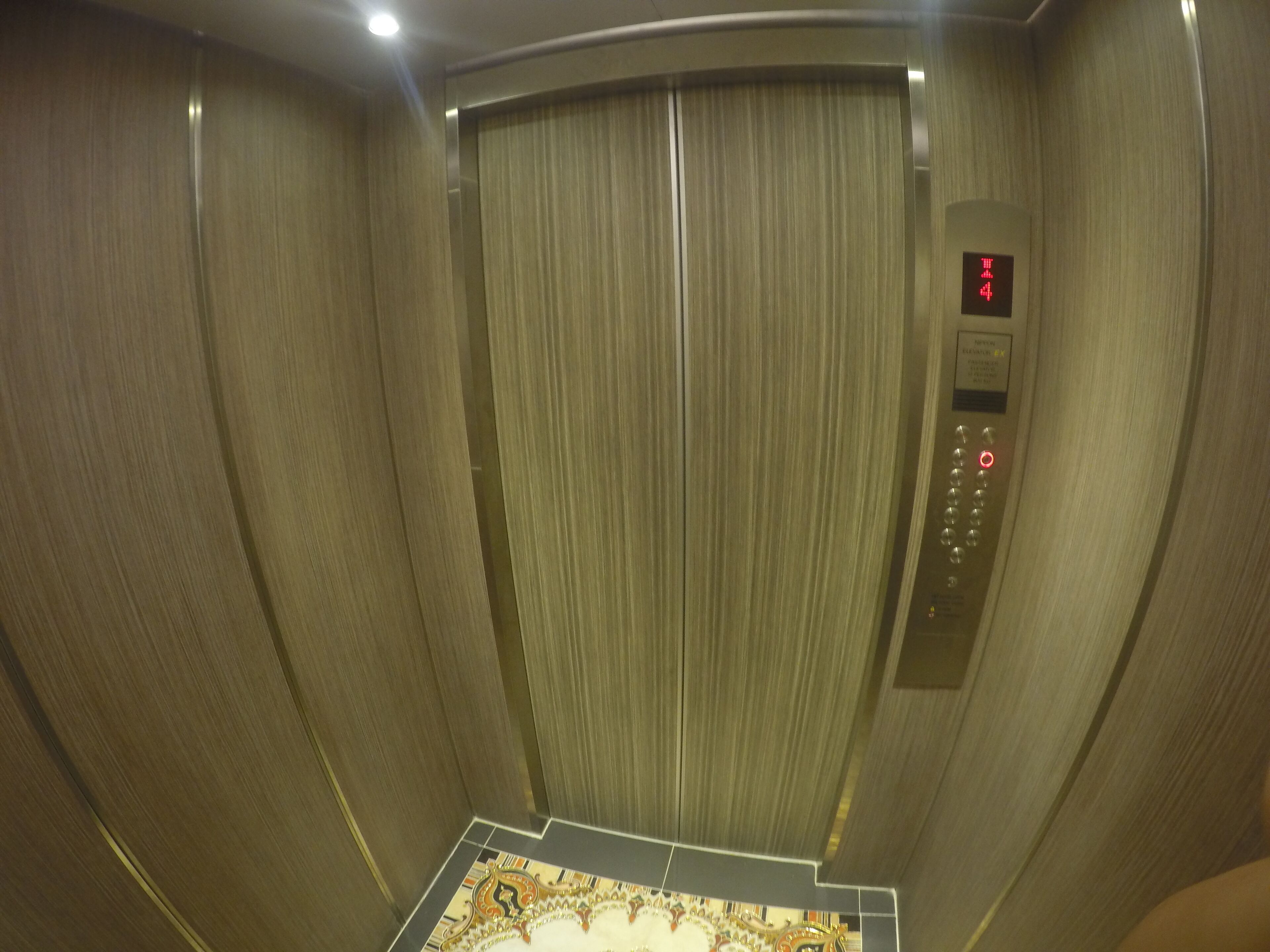 An elevator interior with a control panel displaying a red light and a digital display.