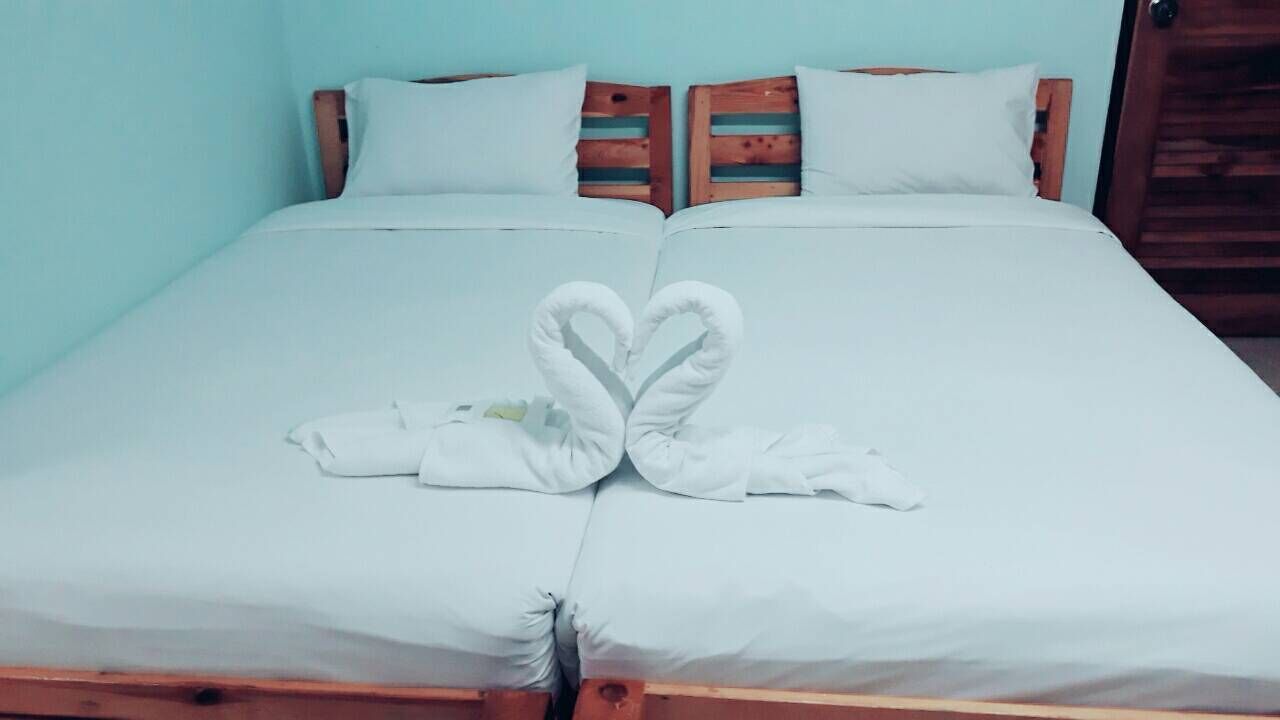Una cama con una toalla dispuesta en forma de corazón y una pluma.