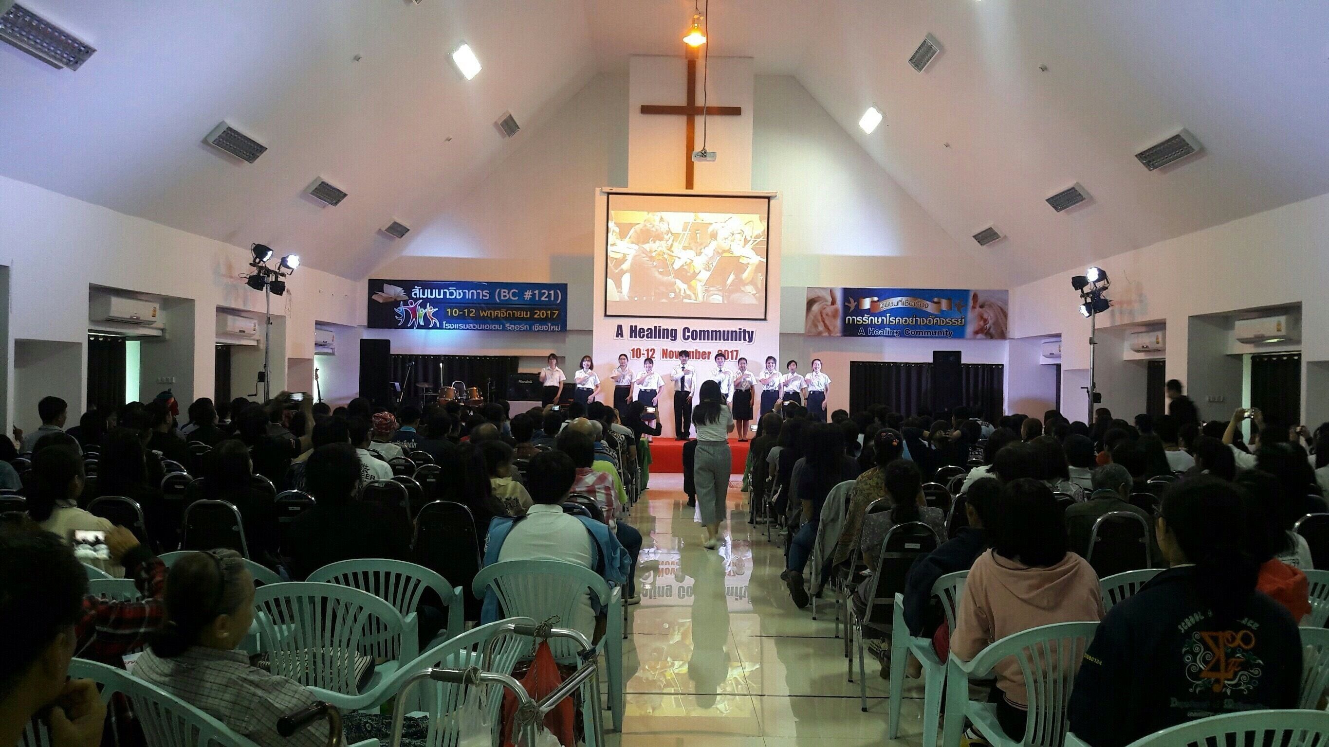 Interior de iglesia con hileras de sillas mirando hacia un escenario para una reunión.