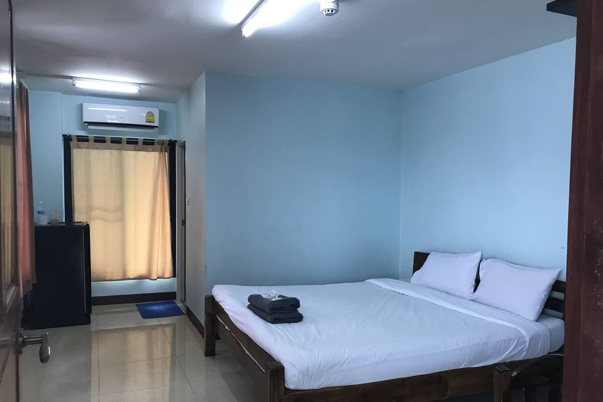 A bedroom with a bed, a wardrobe, and an air conditioning unit.