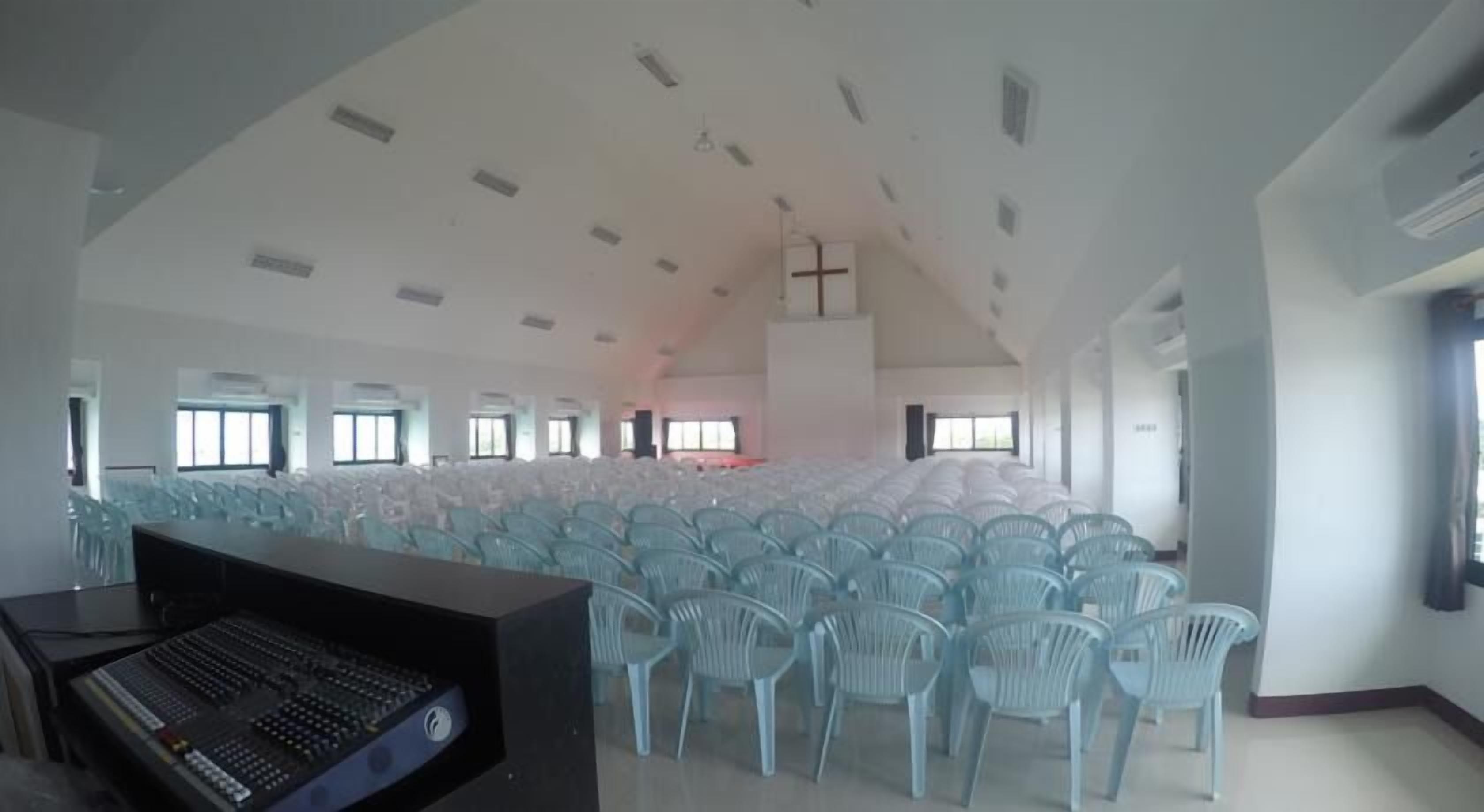 A large hall with rows of chairs and a stage, likely used for events or gatherings.