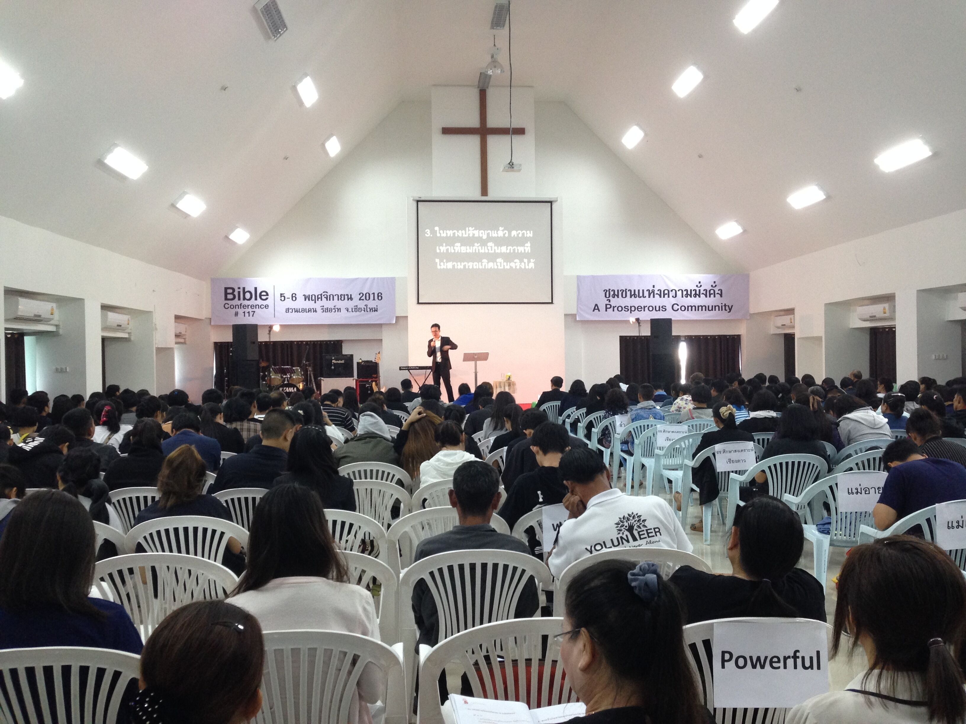 A conference room with rows of white chairs facing a stage.