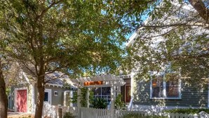 A two-story house with a white picket fence, a covered porch, and a red garage door.
