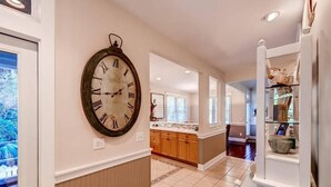 A spacious hallway with a large wall clock, wooden cabinets, and a glass display case.