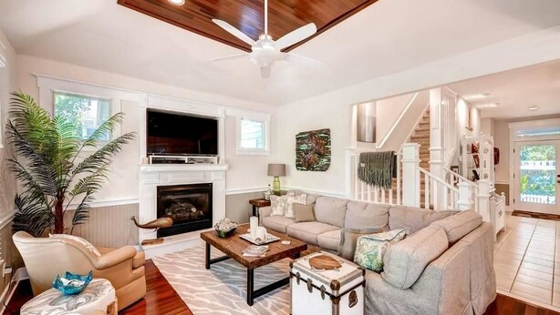A living room with a fireplace, a sofa, a coffee table, and a ceiling fan.