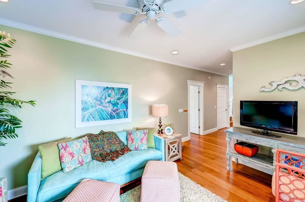 A living room with a light blue sofa, a television, and a ceiling fan.