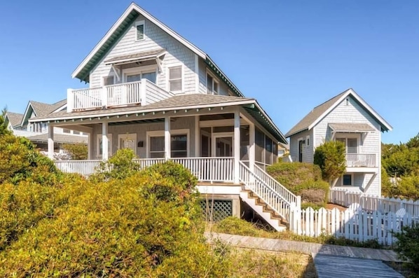A two-story house with a porch, a staircase, and a white picket fence.