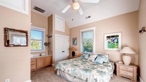 A bedroom with a bed, a ceiling fan, a nightstand, a lamp, a dresser, and a window. - Blue Heron 3 Bedroom Holiday Home By Bald Head Island (Bald Head Island)