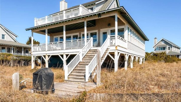 A coastal house with a wooden deck, a covered porch, and a staircase leading to the upper level. - Bogan s on the Beach 4 Bedroom Holiday Home By Bald Head Island (Bald Head Island)