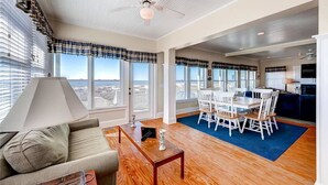 A spacious living area with a dining table and chairs, a sofa, and a ceiling fan. - Bogan s on the Beach 4 Bedroom Holiday Home By Bald Head Island (Bald Head Island)