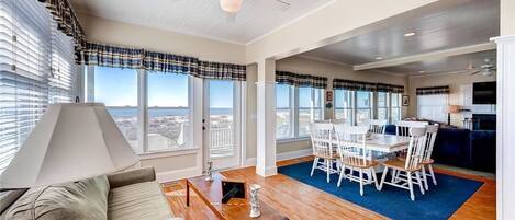 A spacious living area with a dining table and chairs, a sofa, and a ceiling fan.