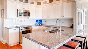 A kitchen with white cabinets, a stainless steel microwave, an oven, and a granite countertop. - Bogan s on the Beach 4 Bedroom Holiday Home By Bald Head Island (Bald Head Island)
