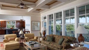 A spacious living room with a large window, a ceiling fan, and a view of the outdoors. - Cape Watch Cottage 4 Bedroom Holiday Home By Bald Head Island (Bald Head Island)