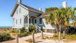 A coastal house with a porch, a sandy pathway, and a palm tree. - Captain Charlie s 1 3 Bedroom Holiday Home By Bald Head Island (Bald Head Island)
