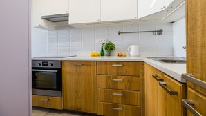 Une cuisine moderne avec des meubles en bois, un four en acier inoxydable et un plan de travail blanc.