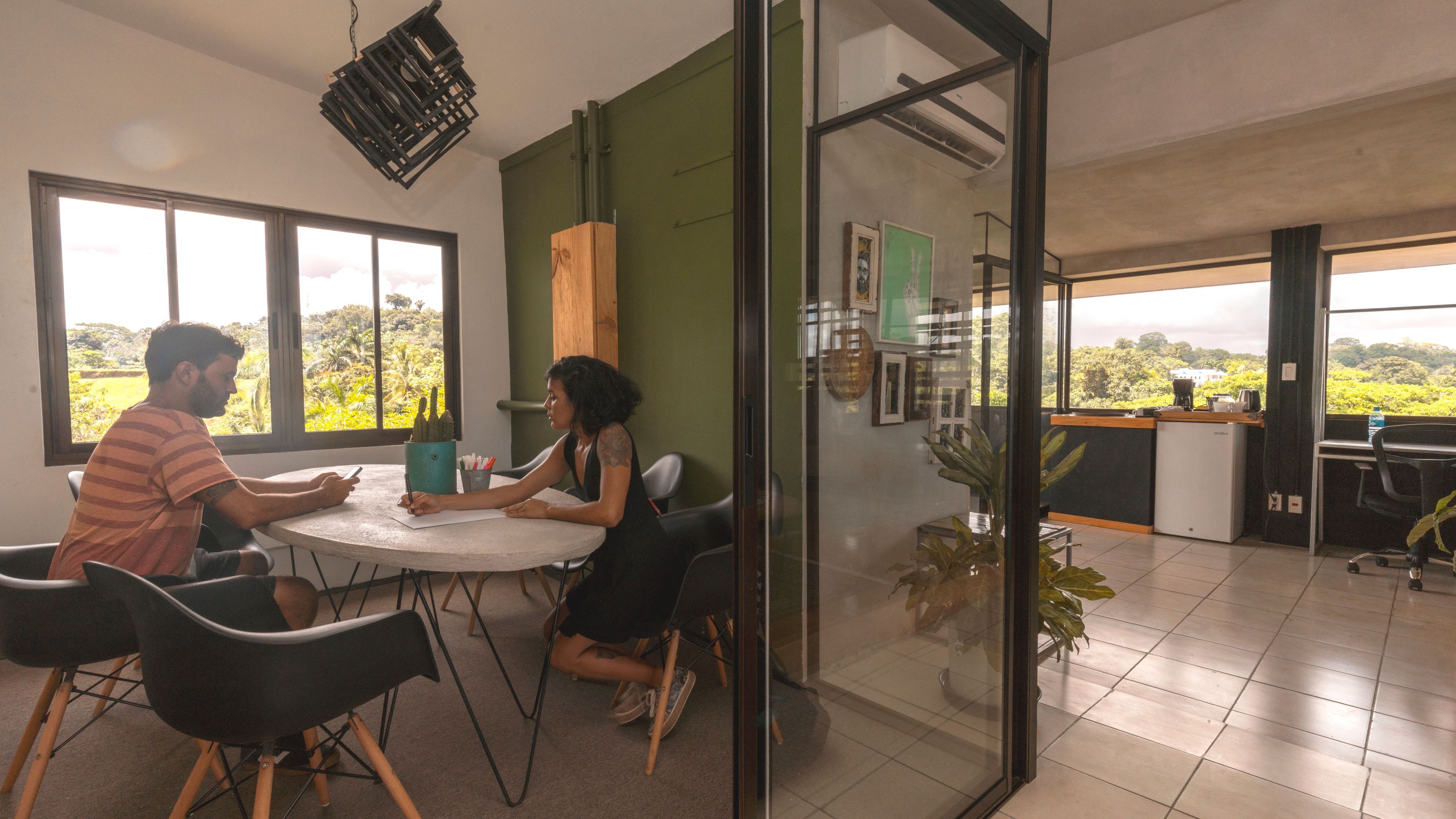 A meeting room with a glass partition, a round table, and chairs.