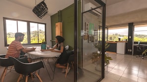 Una sala de reuniones con separador de vidrio, una mesa redonda y sillas.