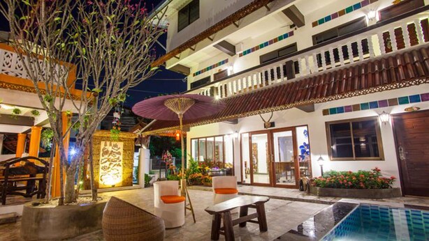 A courtyard with a swimming pool, outdoor seating, and a building with balconies and large windows. - Somwang Boutique House (Chiang Mai)