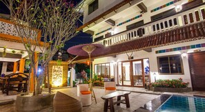 A courtyard with a swimming pool, outdoor seating, and a building with balconies and large windows. - Somwang Boutique House (Chiang Mai)