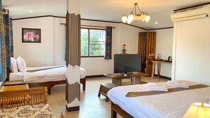 A hotel room with two beds, a TV, a desk, and a window with a view of greenery. - Somwang Boutique House (Chiang Mai)