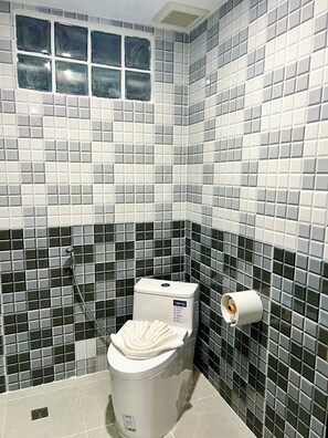 Un baño con inodoro, ducha y soporte para papel higiénico.