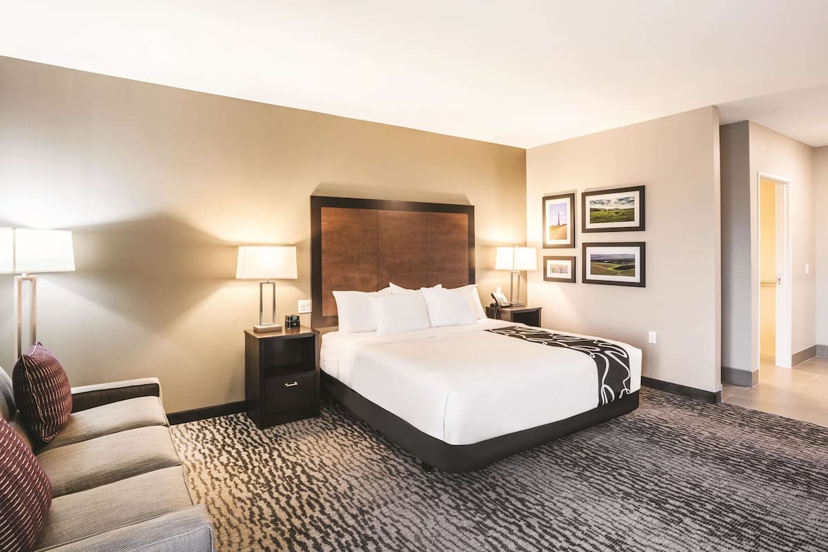 Habitación de hotel con una cama grande, dos mesitas de noche, una lámpara auxiliar y una alfombra estampada.